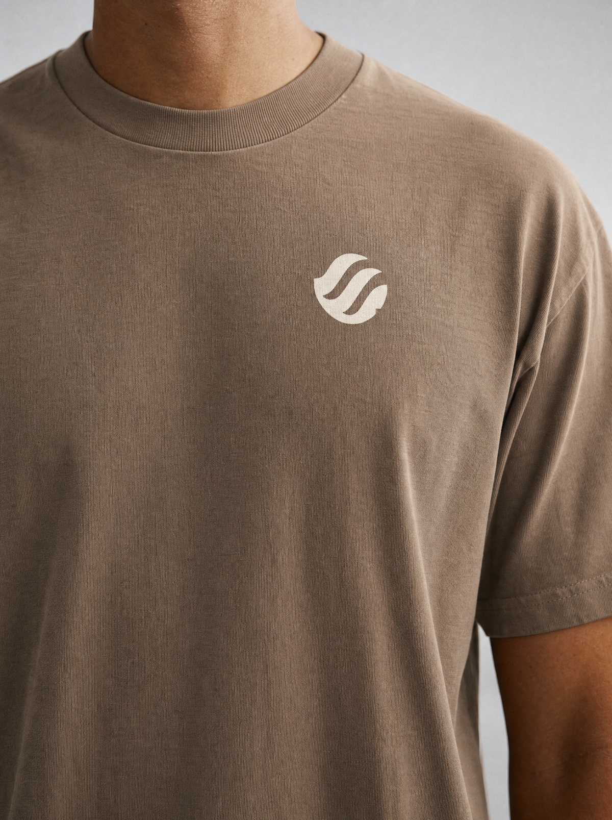 Coast Standard Tee in Sand, close-up of the ivory wave mark and collar
